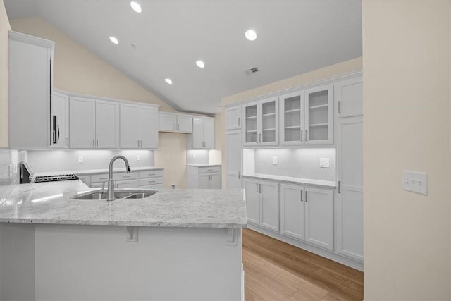 kitchen with white cabinetry, lofted ceiling, sink, and kitchen peninsula