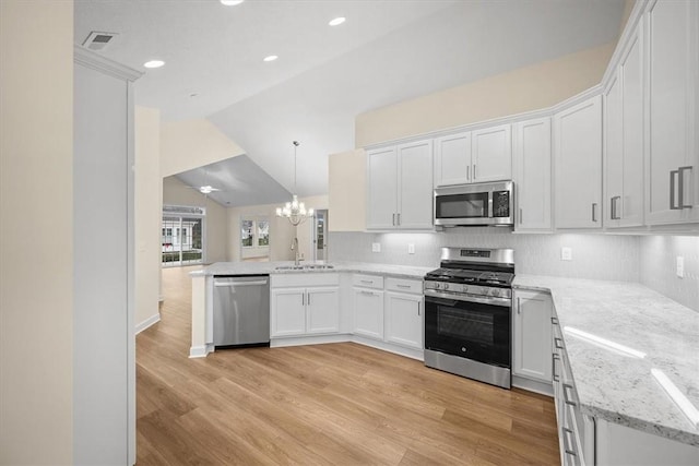 kitchen featuring white cabinets, appliances with stainless steel finishes, lofted ceiling, and kitchen peninsula