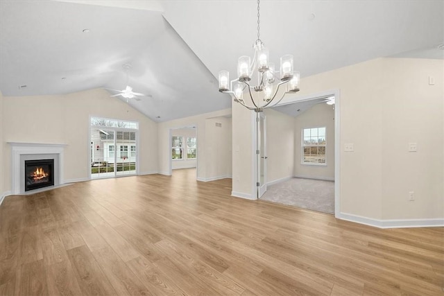 unfurnished living room with lofted ceiling, ceiling fan with notable chandelier, and light hardwood / wood-style floors