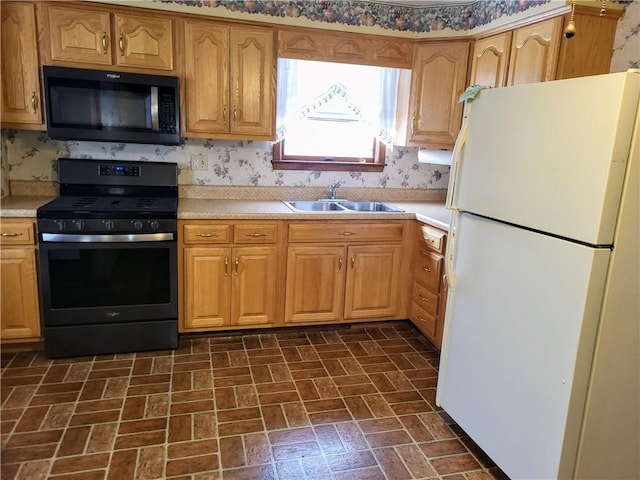 kitchen featuring stove, sink, and white refrigerator