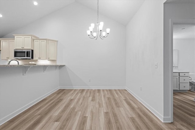 1261 Sandy Ridge Dr, Buffalo Twp, PA 16055 - kitchen with a breakfast bar, light stone counters, high vaulted ceiling, light hardwood / wood-style flooring, and pendant lighting