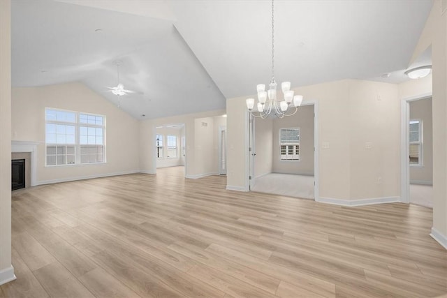 unfurnished living room with ceiling fan with notable chandelier, vaulted ceiling, and light hardwood / wood-style floors