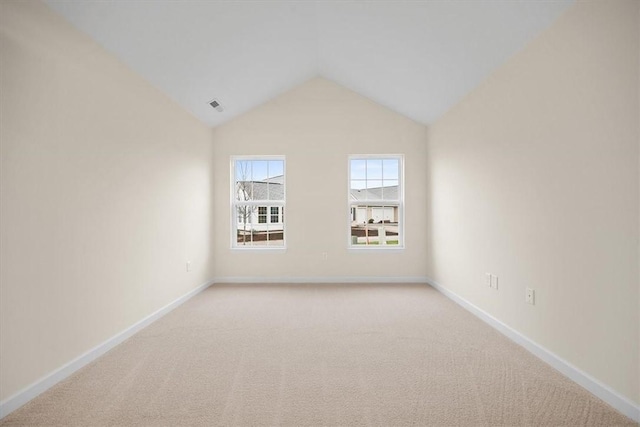 unfurnished room with light colored carpet and vaulted ceiling