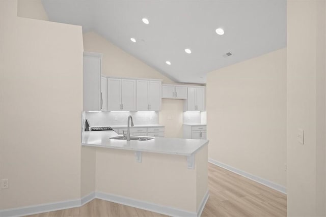 kitchen featuring white cabinetry, sink, light hardwood / wood-style flooring, and decorative backsplash