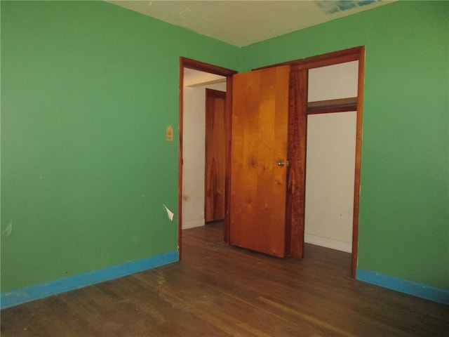 unfurnished bedroom with dark hardwood / wood-style floors and a closet