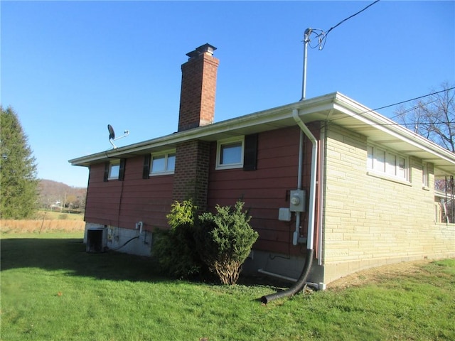 view of side of home featuring cooling unit and a lawn