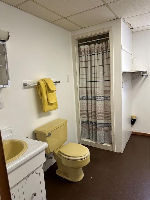 bathroom with a shower with curtain, vanity, toilet, and a drop ceiling