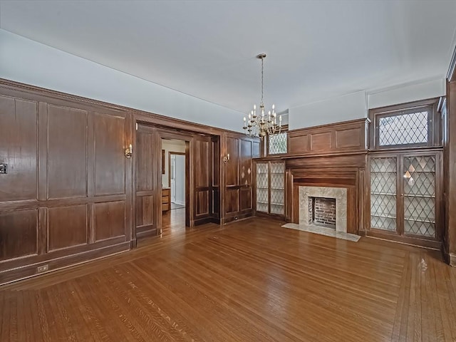 unfurnished living room with dark hardwood / wood-style flooring, an inviting chandelier, and a fireplace