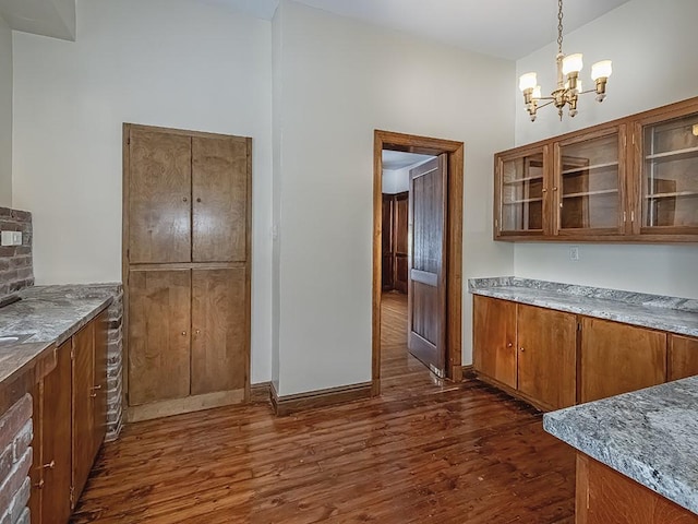 kitchen with hanging light fixtures, light stone countertops, a chandelier, and dark hardwood / wood-style flooring