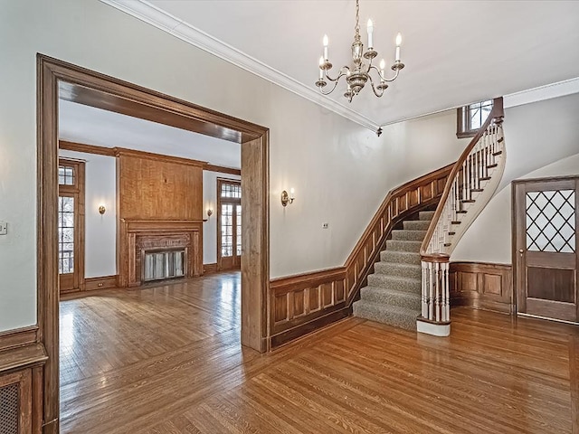 staircase featuring ornamental molding, wood-type flooring, and a chandelier