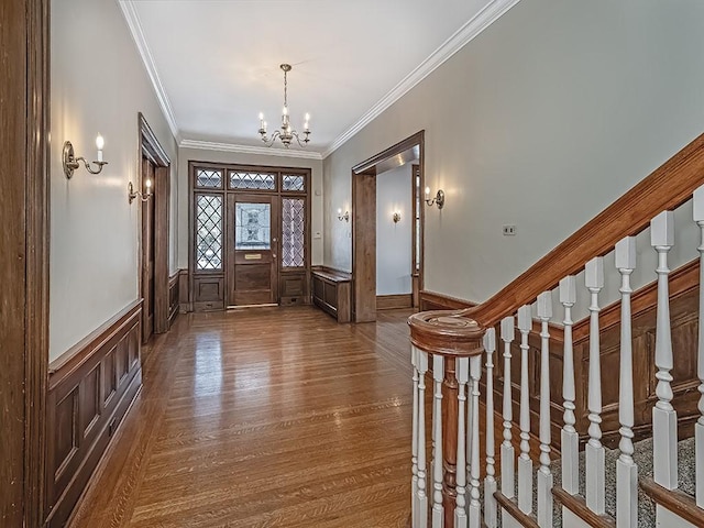 entryway featuring hardwood / wood-style flooring, ornamental molding, and a chandelier