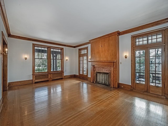 unfurnished living room featuring hardwood / wood-style flooring, crown molding, and french doors