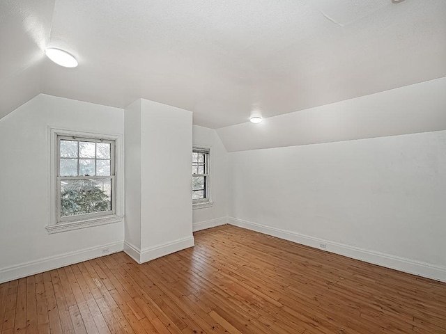 additional living space with lofted ceiling, plenty of natural light, and hardwood / wood-style floors