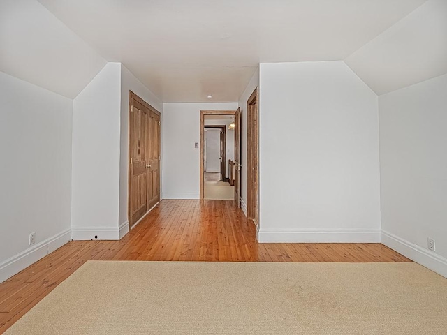 additional living space with hardwood / wood-style flooring and vaulted ceiling