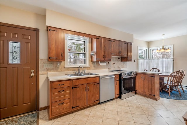 kitchen featuring stainless steel appliances, hanging light fixtures, sink, and backsplash