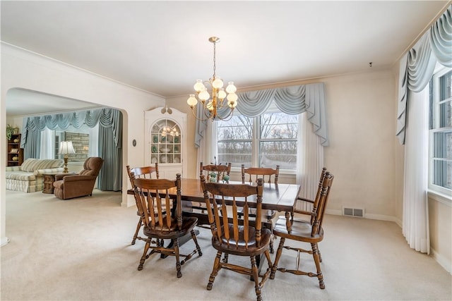 dining space with an inviting chandelier, crown molding, and light colored carpet