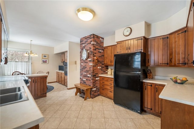 kitchen with black refrigerator, decorative light fixtures, sink, and a notable chandelier