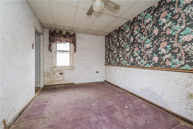 empty room featuring a paneled ceiling and ceiling fan