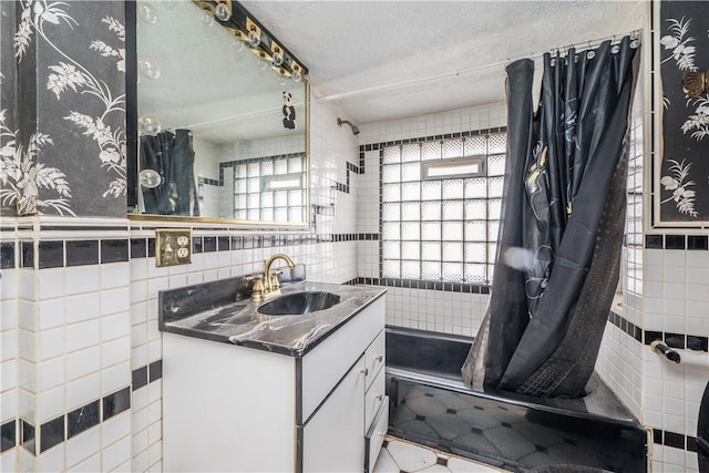 bathroom with vanity, tile walls, shower / tub combo, and a textured ceiling