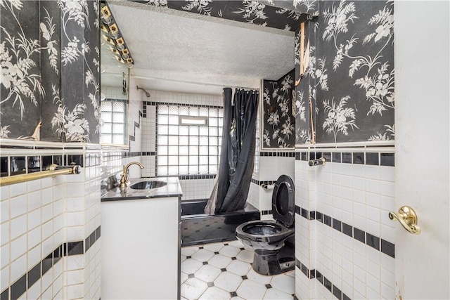 bathroom featuring vanity, tile walls, a textured ceiling, and toilet