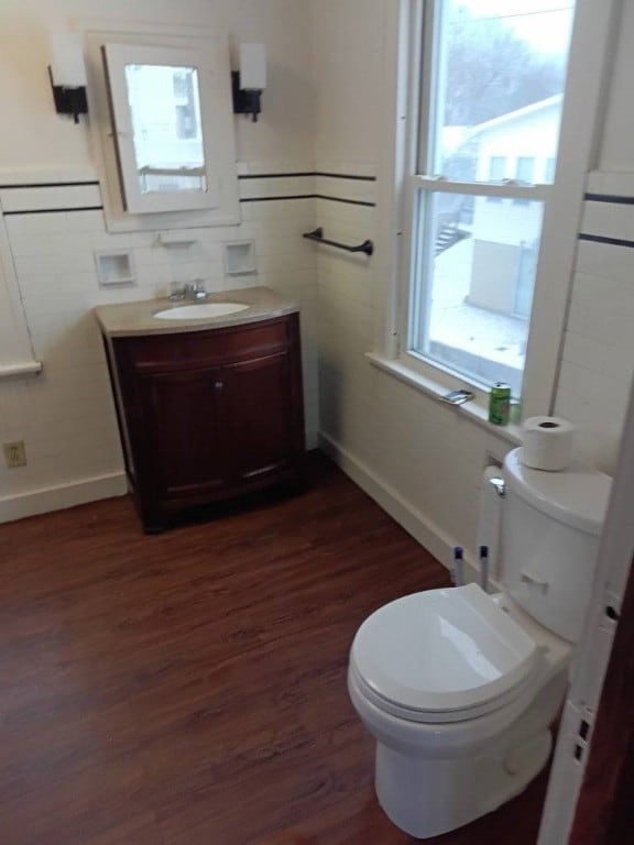 bathroom featuring hardwood / wood-style flooring, vanity, toilet, and tile walls