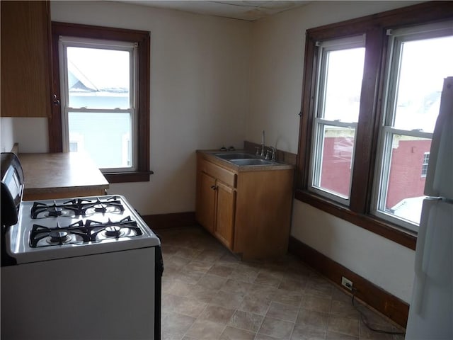 kitchen with white appliances, a healthy amount of sunlight, and sink