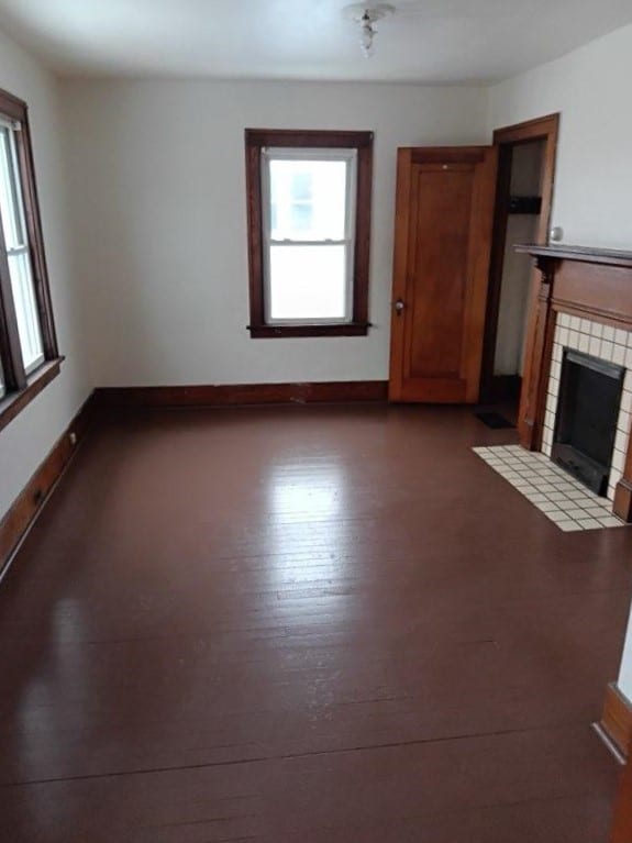 unfurnished living room with a tiled fireplace and light hardwood / wood-style floors