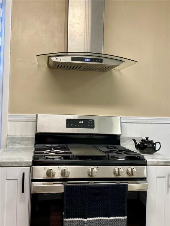 kitchen with white cabinets, exhaust hood, and stainless steel gas stove