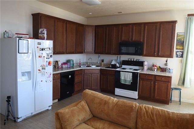 kitchen featuring open floor plan, light countertops, a sink, and black appliances