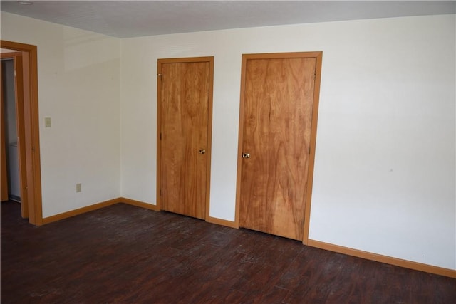 unfurnished bedroom with baseboards and dark wood finished floors