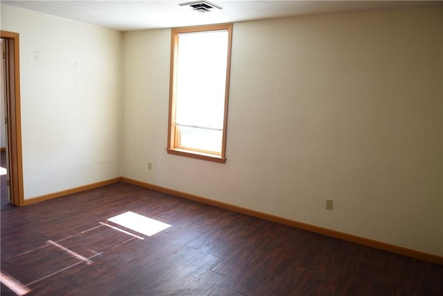 empty room featuring visible vents, baseboards, and wood finished floors