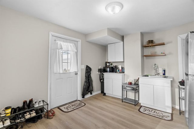 kitchen featuring white cabinetry, sink, and light wood-type flooring