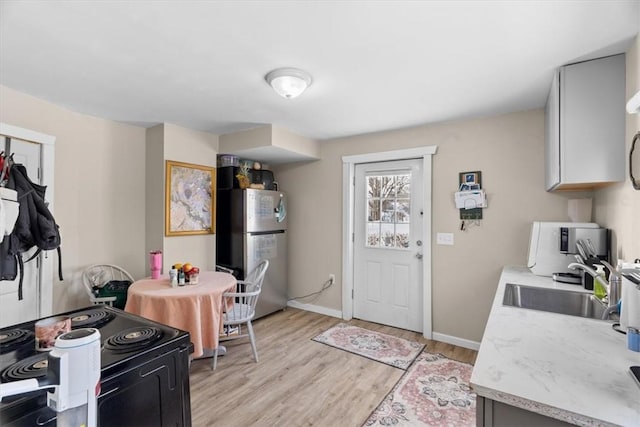 kitchen with sink, electric range, stainless steel refrigerator, and light wood-type flooring