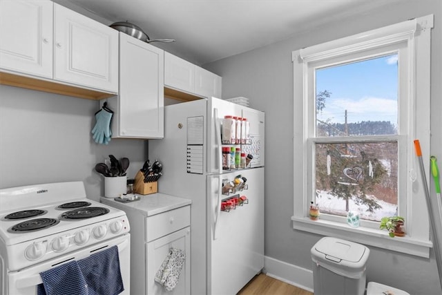 kitchen with white appliances, light hardwood / wood-style flooring, and white cabinets