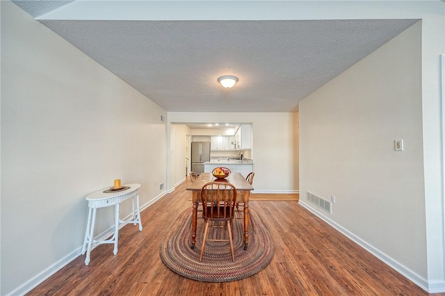 unfurnished dining area featuring wood-type flooring and a textured ceiling