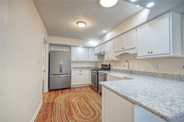 kitchen with sink, white cabinetry, a textured ceiling, light wood-type flooring, and stainless steel appliances