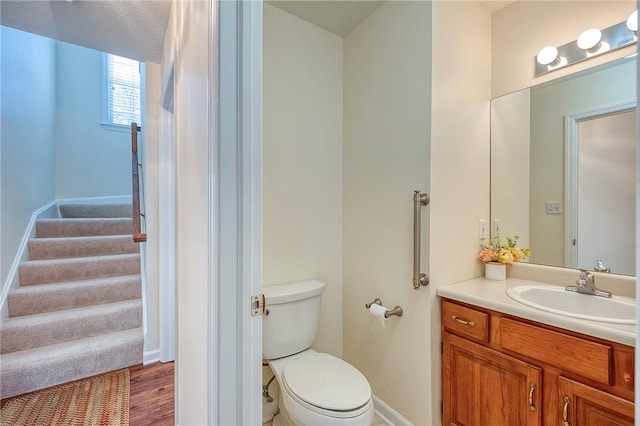 bathroom with wood-type flooring, vanity, a textured ceiling, and toilet