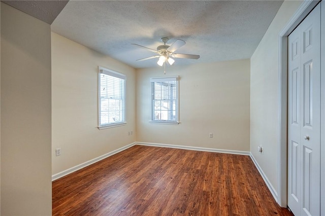 spare room featuring dark hardwood / wood-style flooring, ceiling fan, and a textured ceiling