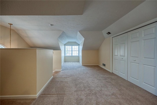 bonus room with light colored carpet, vaulted ceiling, and a textured ceiling