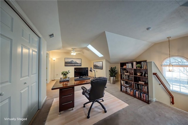 carpeted office with vaulted ceiling with skylight