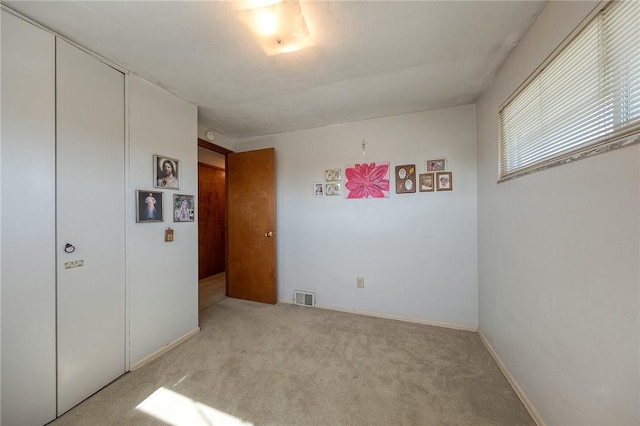 unfurnished bedroom featuring light carpet and a closet