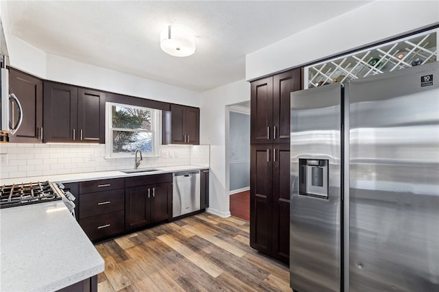 kitchen with tasteful backsplash, sink, dark hardwood / wood-style flooring, dark brown cabinetry, and stainless steel appliances