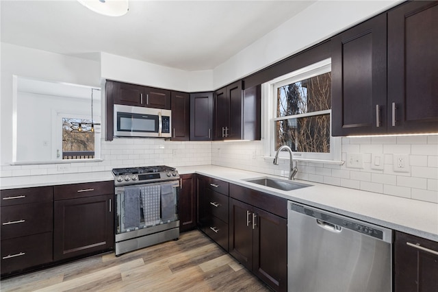 kitchen featuring sink, dark brown cabinets, light hardwood / wood-style flooring, stainless steel appliances, and decorative backsplash