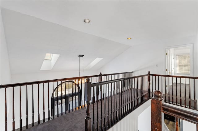 corridor featuring a notable chandelier, carpet floors, and vaulted ceiling with skylight