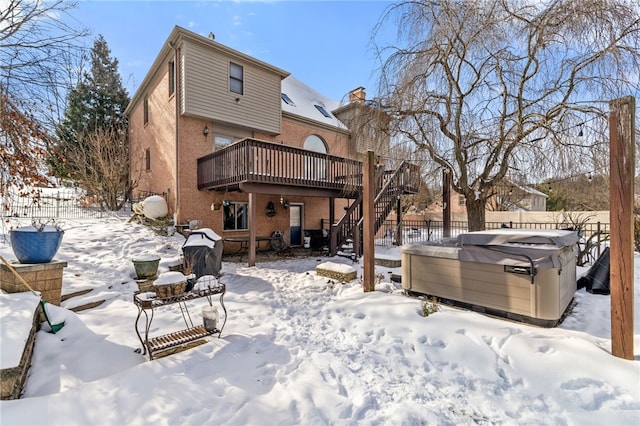 snow covered rear of property featuring a hot tub and a deck