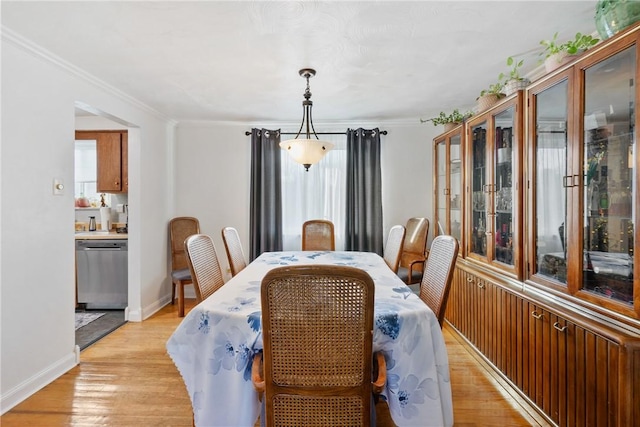 dining room with ornamental molding and light hardwood / wood-style flooring