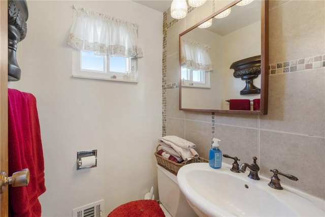 bathroom with decorative backsplash, sink, and tile walls