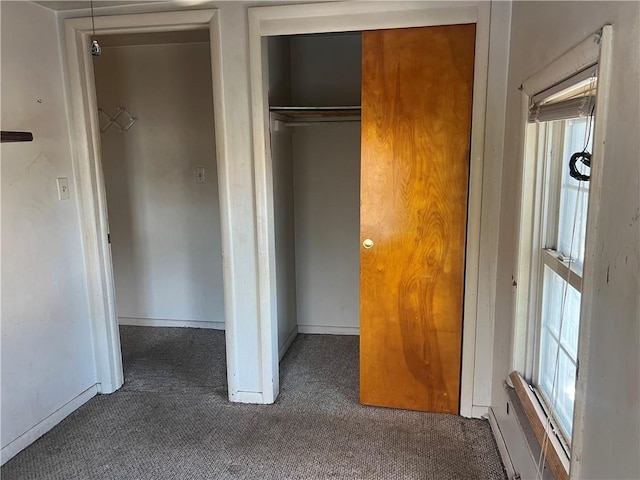 unfurnished bedroom featuring dark carpet and a closet