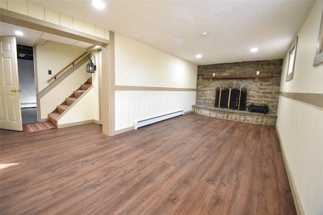 unfurnished living room featuring a fireplace, a baseboard radiator, and wood-type flooring