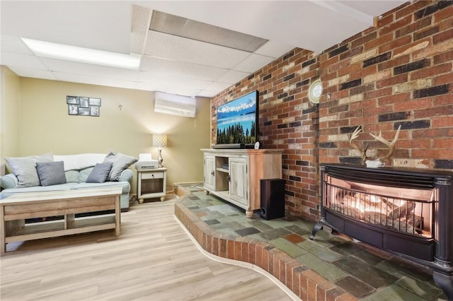 living room featuring a fireplace, hardwood / wood-style flooring, and a paneled ceiling